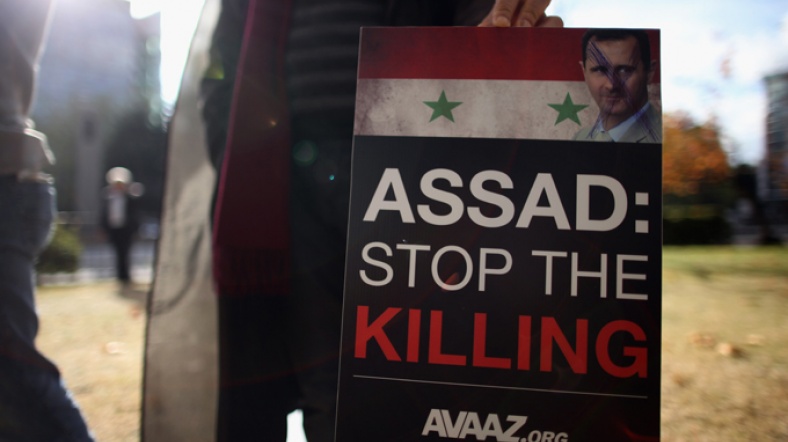 Bir protestocunun elinde Avaaz.org'un Esad: Ölümleri durdur pankartı.