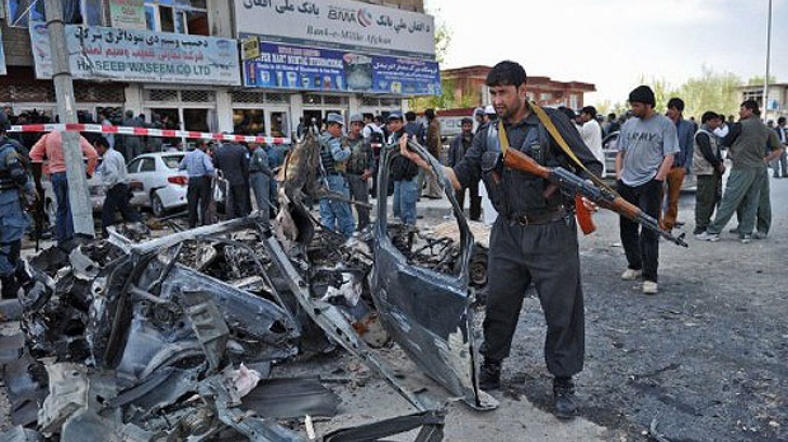 Afgan polisi parçalanmış bir otomobilin enkazını kaldırıyor.