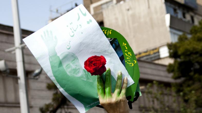 İranlı bir kadın elinde kırmızı gül ile Mir Hüseyin Musavi posterini havaya kaldırıyor.