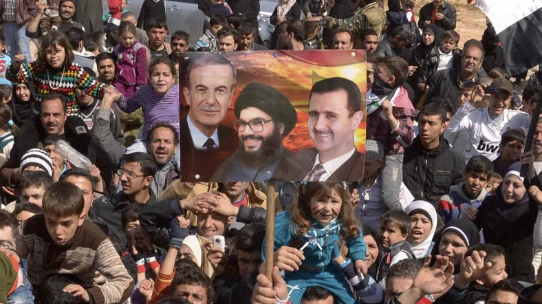 Hafız Esad, Hasan Nasrallah ve Beşar Esad fotoğraflarından oluşan bir kolaj dövizi taşıyan Suriye rejimi destekçisi protestocular.
