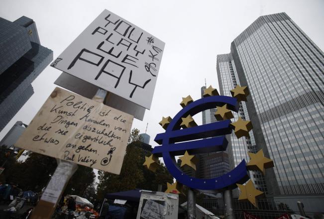 Avrupa Merkez Bankası önündeki Euro işareti ve yanında protestocuların taşıdığı dövizler.
