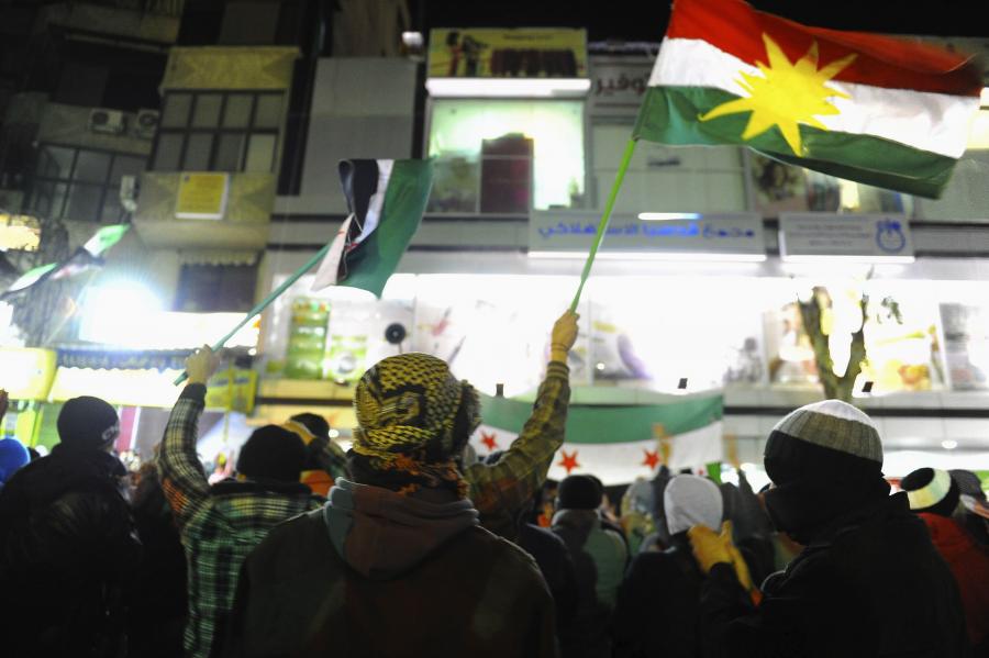 Protestocular Kürt ve Baas Partisi öncesi Suriye bayraklarını sallıyor.